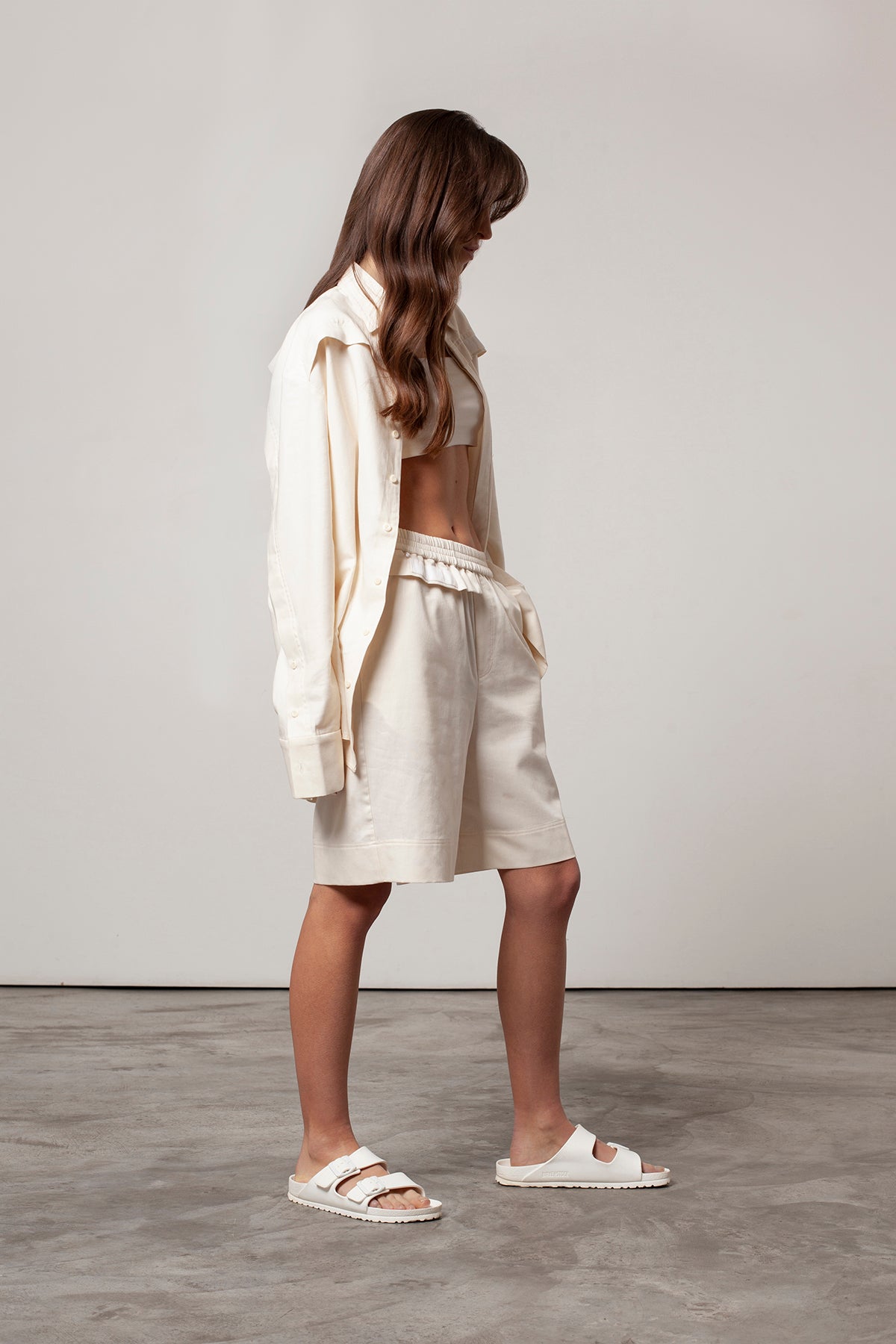 Léa is wearing White Canvas sustainable natural beige color, organic cotton, genderless, inclusive, casual short, size S styled with the essential shirt and natural jersey crop top. The Essential short has minimal modern aesthetics design allowing comfort and bringing self-confidence. A limited-edition production is made locally in France to reduce environmental impact and guarantee high quality and durability of the products.