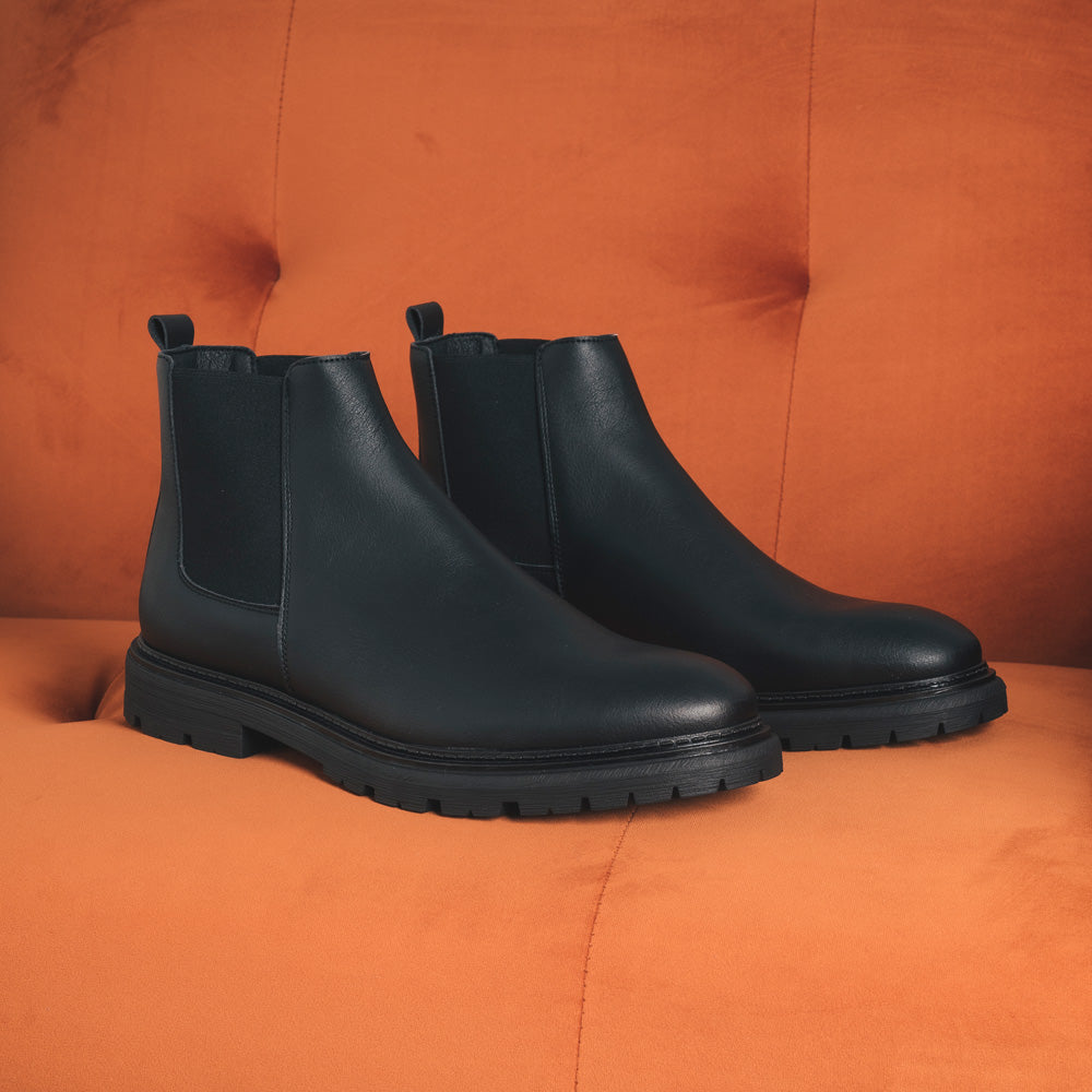 Men vegan ankle boots made with black sustainable microfiber on a couch | NAE