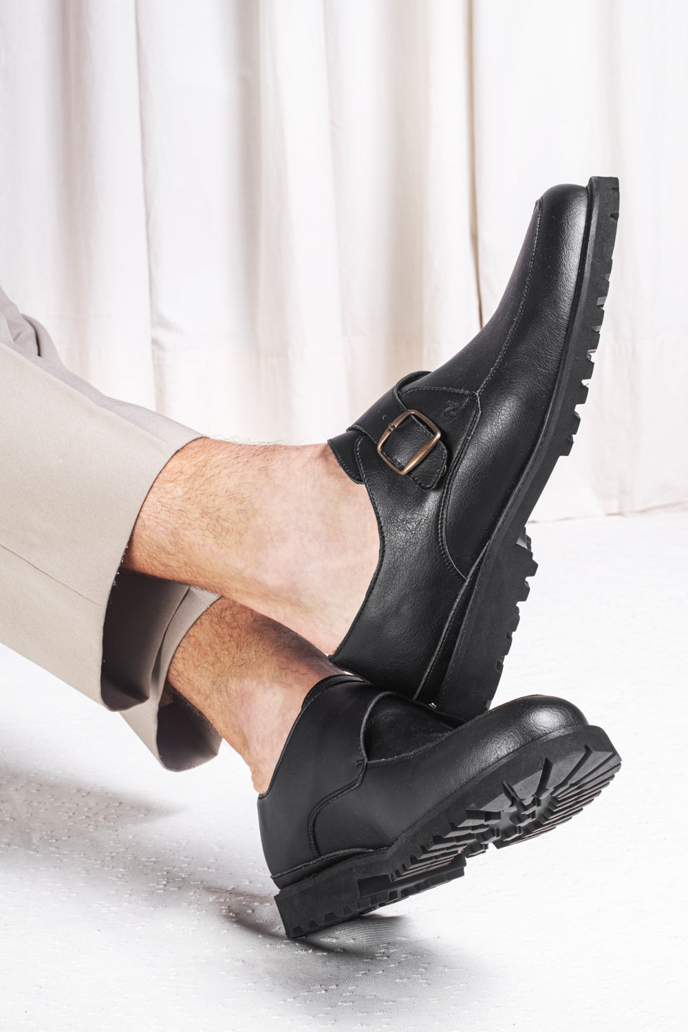 crossed foots wearing vegan black loafers with pants from NAE Vegan Shoes