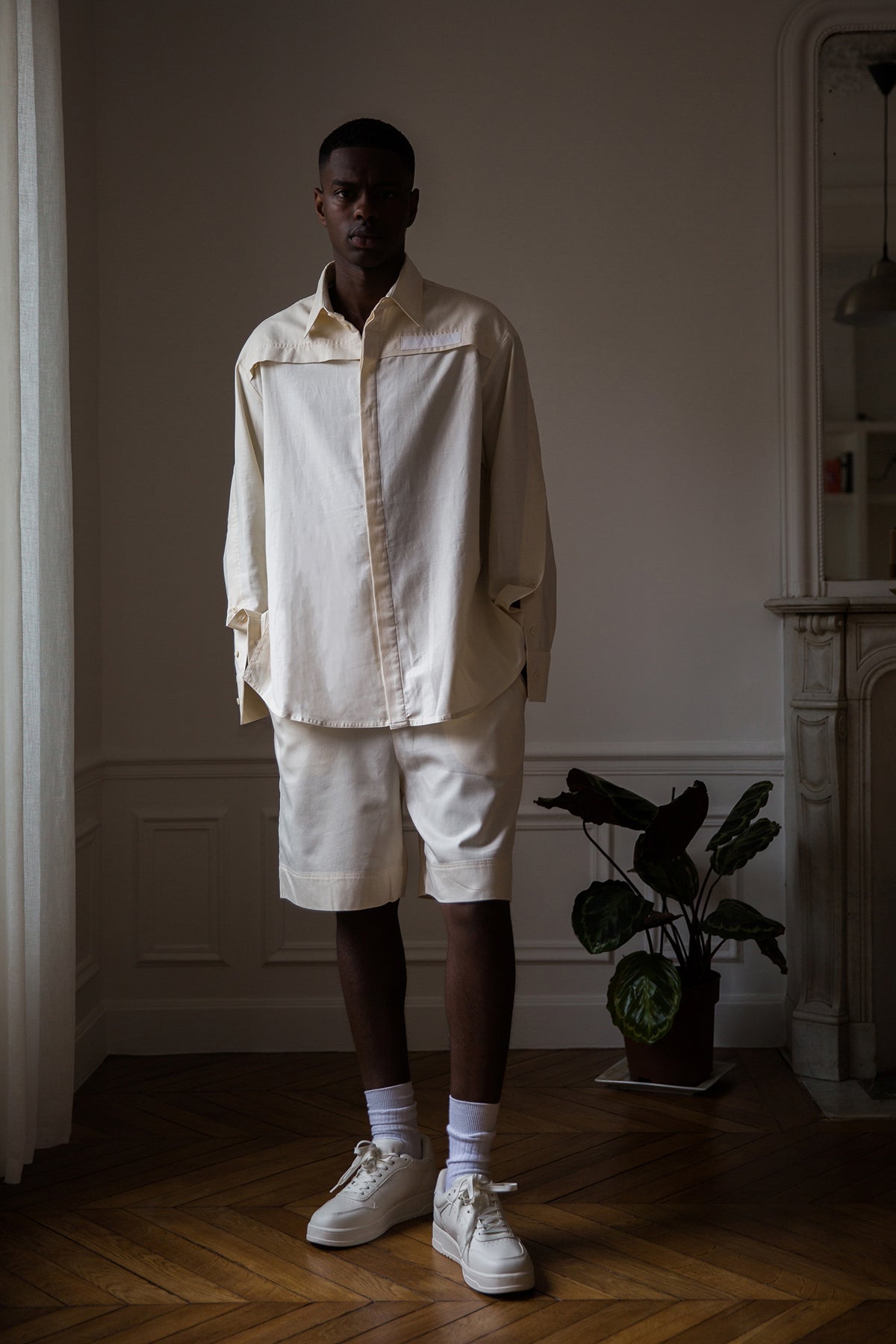 Thierno is wearing White Canvas sustainable natural beige color, organic cotton, genderless, inclusive, casual short, size M styled with a white tank top. The Essential short has minimal modern aesthetics design allowing comfort and bringing self-confidence. A limited-edition production is made locally in France to reduce environmental impact and guarantee high quality and durability of the products.