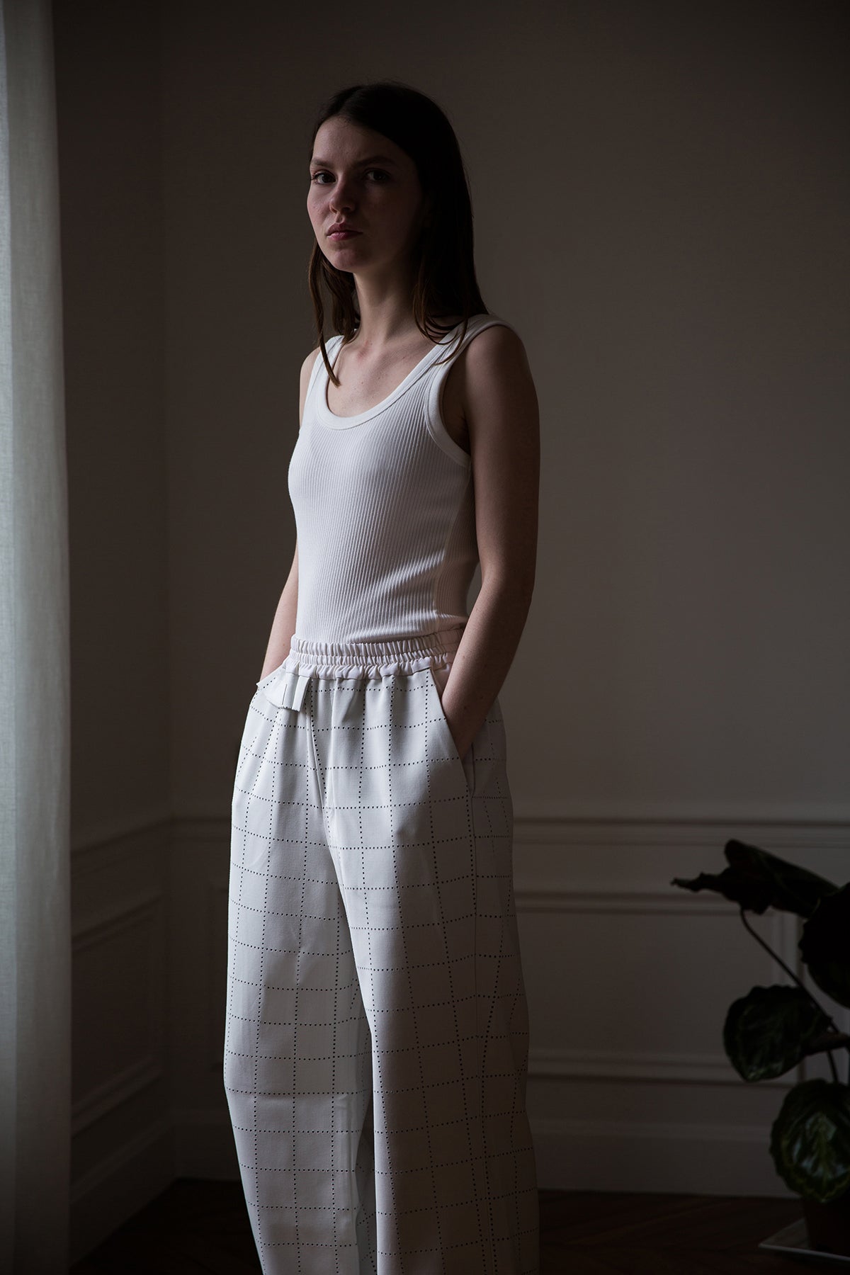 Dalva is wearing White Canvas sustainable light grey color, genderless, seasonless casual checks trousers, size S. The Essential checks trousers have minimal modern aesthetics design allowing comfort and bringing self-confidence. This unique piece is made locally in Paris to reduce environmental impact and guarantee high quality and durability of the products.