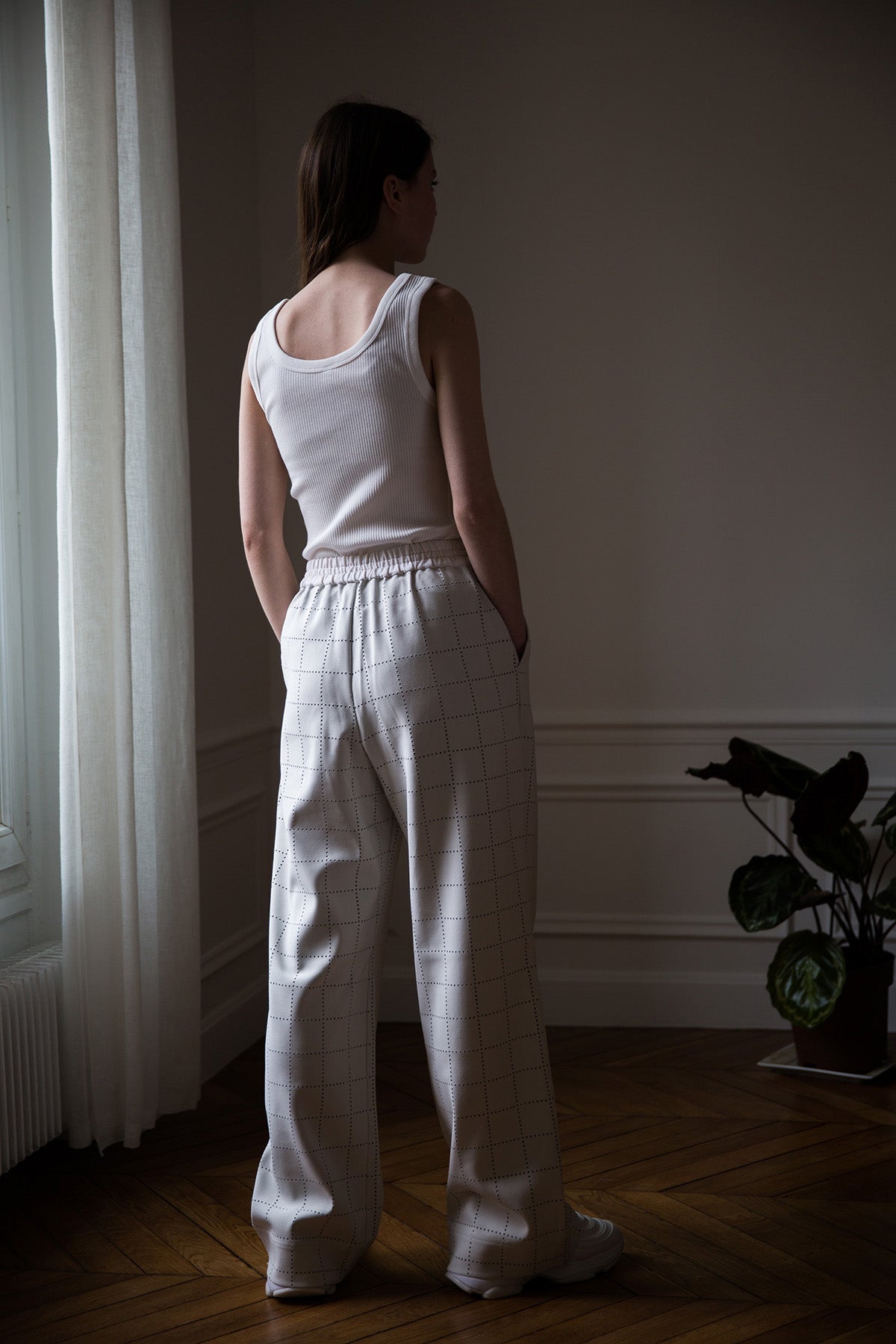 Dalva is wearing White Canvas sustainable light grey color, genderless, seasonless casual checks trousers, size S. The Essential checks trousers have minimal modern aesthetics design allowing comfort and bringing self-confidence. This unique piece is made locally in Paris to reduce environmental impact and guarantee high quality and durability of the products.