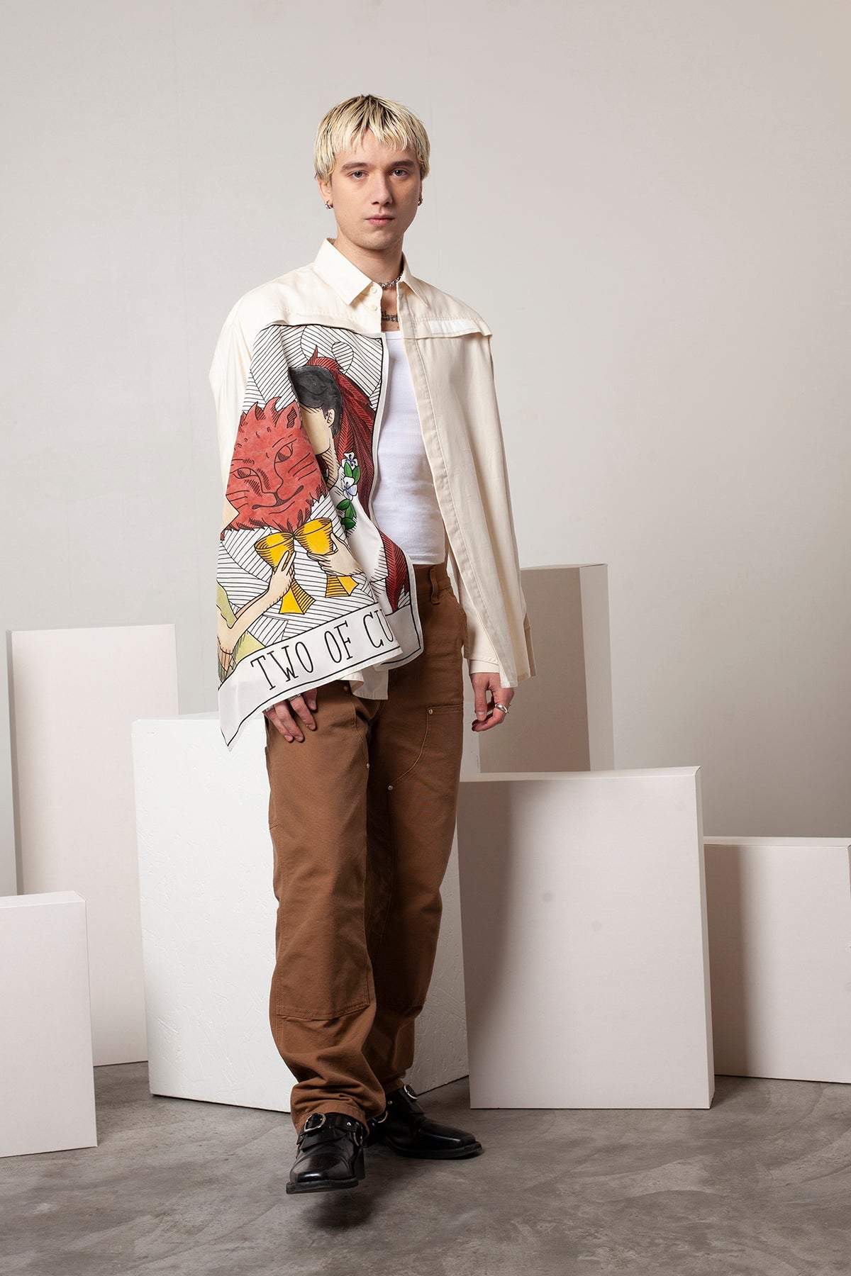 Clément is wearing the White Canvas ESSENTIAL SHIRT styled with THE TWO OF CUPS foulard and square panel made from leftover deadstock silk fabric. The foulard has an exclusive design inspired by tarot cards drawn by the artist Maria Robla, printed with black artisanal eco-friendly ink locally in Paris and hand painted by the artist. Wear the foulard alone or attach it to the essential pieces to personalize them and wear them your unique way. Your perfect summer accessory. White Canvas x Maria Robla.