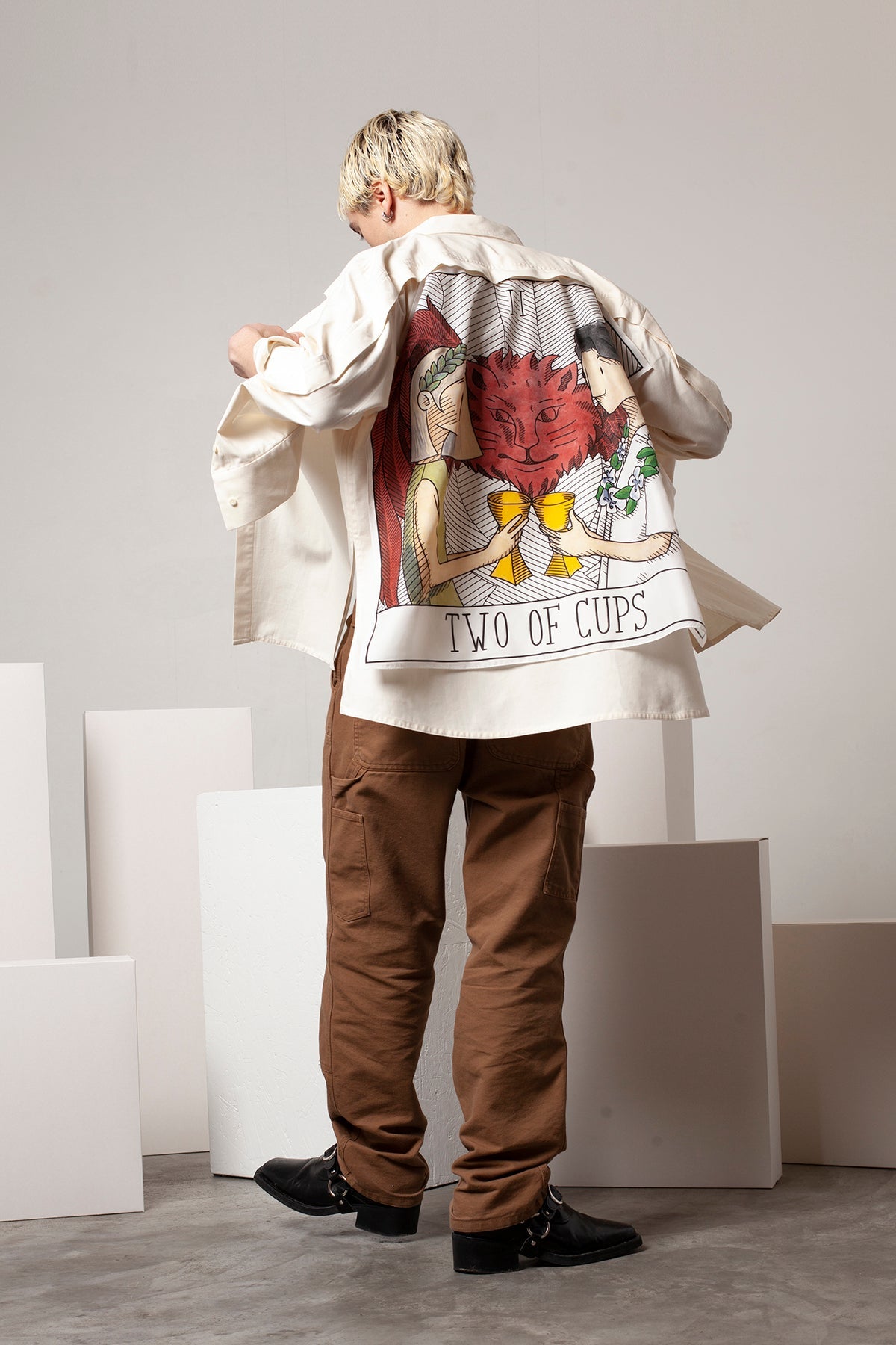 Clément is wearing the White Canvas ESSENTIAL SHIRT styled with THE TWO OF CUPS foulard and square panel made from leftover deadstock silk fabric. The foulard has an exclusive design inspired by tarot cards drawn by the artist Maria Robla, printed with black artisanal eco-friendly ink locally in Paris and hand painted by the artist. Wear the foulard alone or attach it to the essential pieces to personalize them and wear them your unique way. Your perfect summer accessory. White Canvas x Maria Robla.