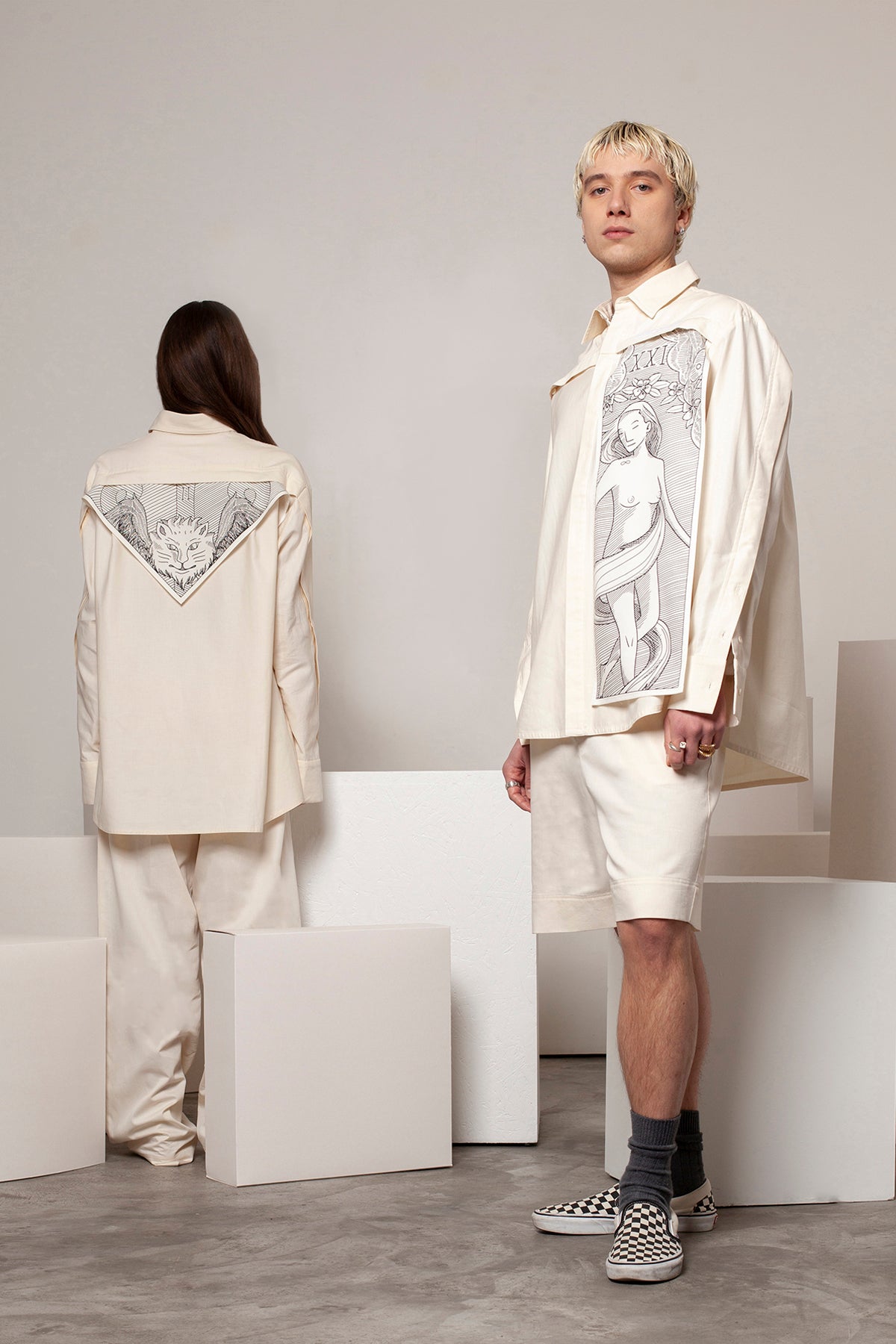 Clément is wearing the White Canvas ESSENTIAL SHIRT styled with THE WORLD vertical panel made from leftover deadstock white cotton poplin. The panel has an exclusive design inspired by tarot cards drawn by the artist Maria Robla and printed with black artisanal eco-friendly ink locally in Paris in collaboration with RoStudio. Attach the black and white panel to the essential pieces to personalize them and wear them your unique way. Your perfect summer accessory.