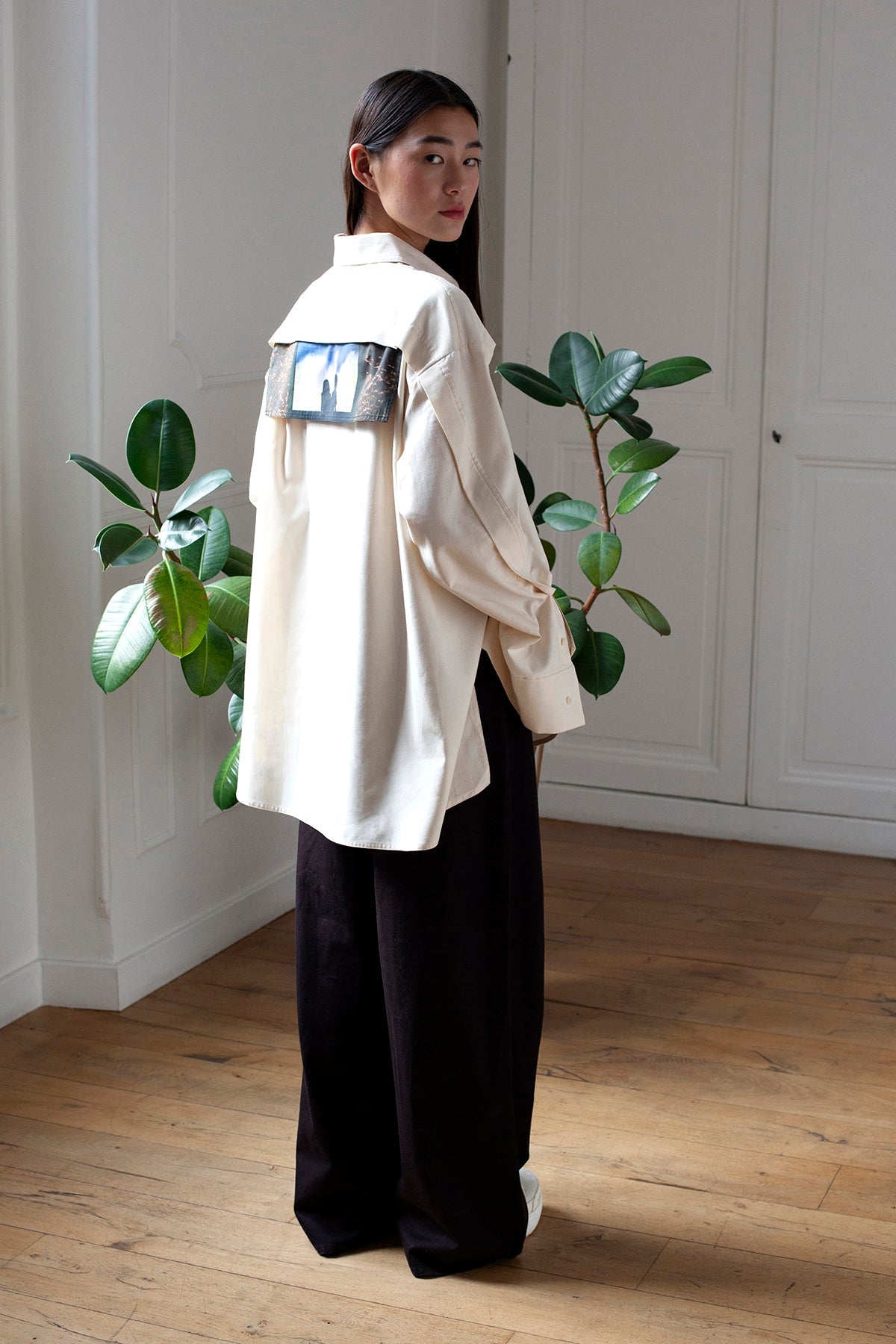 SiJia is wearing the White Canvas ESSENTIAL SHIRT styled with the Shadows horizontal panel made from deadstock white cotton poplin. The panel has an exclusive print of a photo by the photographer Henrique Soares. Attach the panel to the essential pieces to personalize them and wear them your unique way. It is the perfect creative autumn accessory.