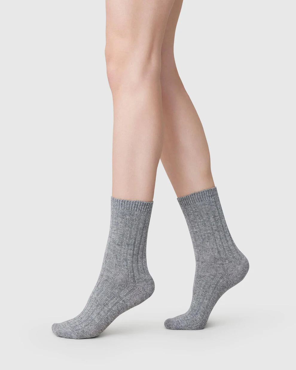 Une femme porte les chaussettes grises fabriquées en Italie, en coloris gris, de profil. 