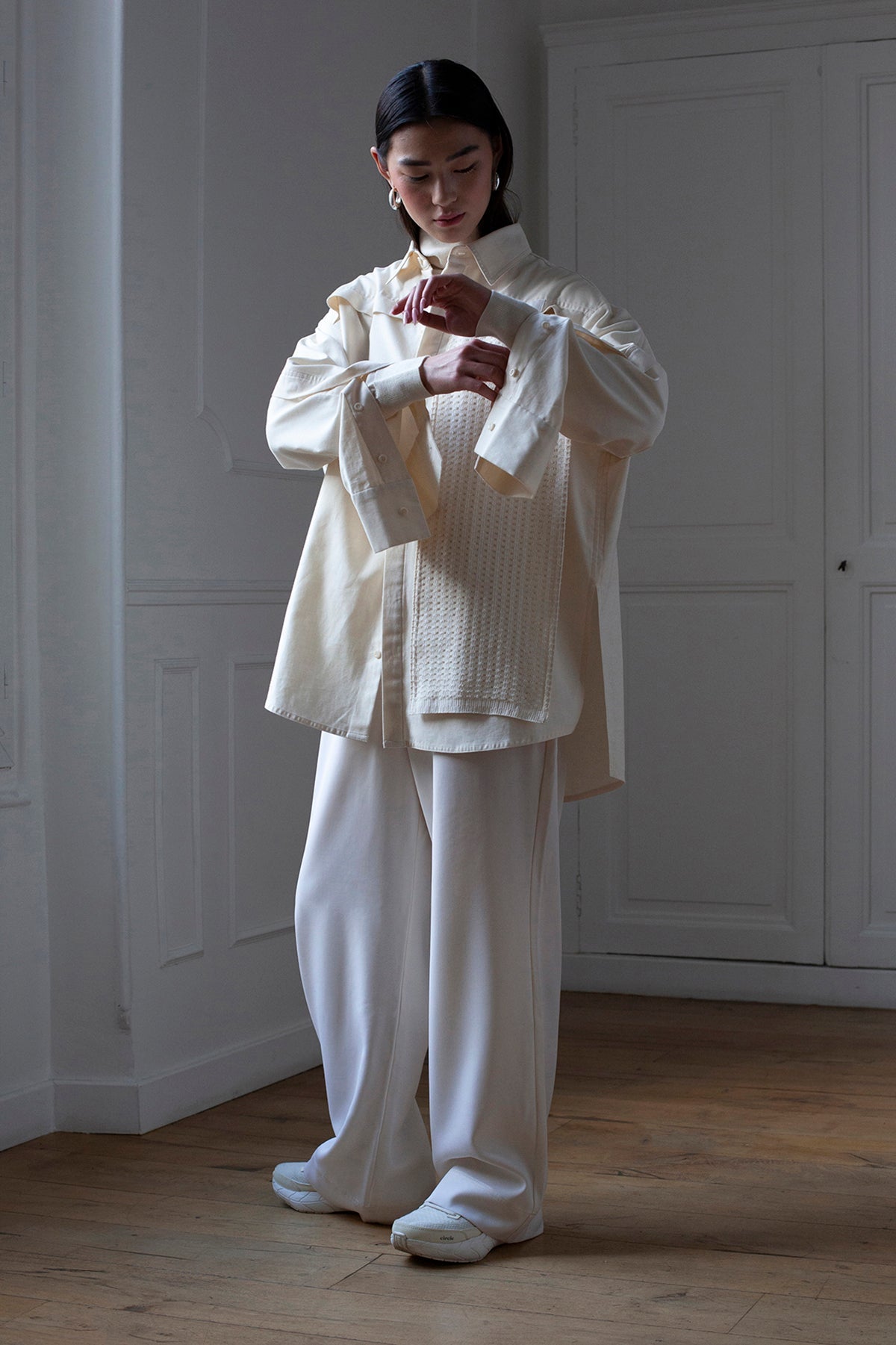 SiJia is wearing White Canvas sustainable natural beige color, organic cotton oversized, genderless, inclusive, seasonless casual shirt, size S/M styled with wool trousers. The Essential shirt has minimal modern aesthetics design allowing comfort and bringing self-confidence. A limited-edition production is made locally in France to reduce environmental impact and guarantee high quality and durability of the products. 